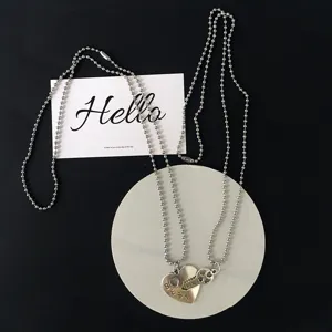 Detailed close-up shot of matching couple bead chain necklace with heart key pendant.