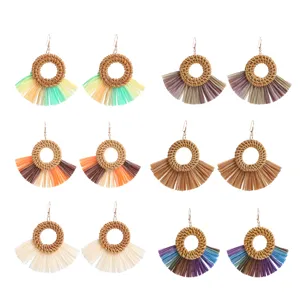 Gedetailleerd overzicht van handgeweven rotan en raffia kwastjes oorbellen voor de zomer.