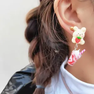 Gros plan de boucles d'oreilles ours fraise milk-shake faites à la main, style doux.