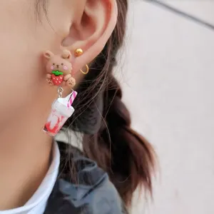 Gros plan détaillé des boucles d'oreilles mignonnes ours fraise et thé aux perles.