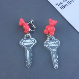 Cute resin bear and glitter key pendant clip-on earrings detail shot for women.