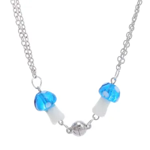 Gedetailleerde close-up van de dubbele metalen ketting met blauwe paddenstoel hanger.