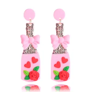 Detailansicht der süßen rosa Weinflasche Ohrringe mit hübscher Schleife und rotem Rosenmotiv.