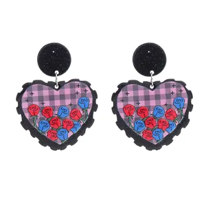 Vue détaillée de boucles d'oreilles cœur en acrylique avec motif floral et à carreaux roses.