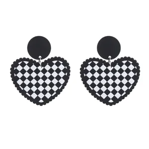 Vue détaillée de boucles d'oreilles en acrylique cœur à carreaux noirs et blancs, bijoux chics.