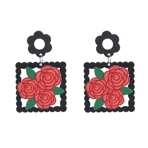 Gros plan détaillé de boucles d'oreilles en acrylique avec motif de roses rouges et clou fleur.