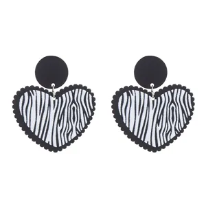 Gros plan détail de boucles d'oreilles cœur en acrylique zébré noir et blanc, style.