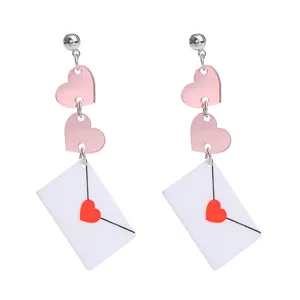 Nahaufnahme der Acryl-Briefumschlag- und rosa Herz-Ohrringe mit einem süßen Valentin-Design.