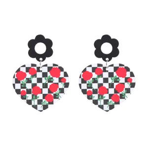 Vue rapprochée de boucles d'oreilles cœur à carreaux et roses rouges avec tiges fleurs.