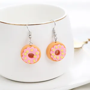 Detailansicht handgefertigter Fimo Donut Ohrringe, süßer Stil, rosa und gelbe Akzente.
