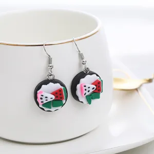 Nahaufnahme kreativer handgemachter Fimo Fruchtkuchen Ohrringe auf weißer Tasse Präsentation.
