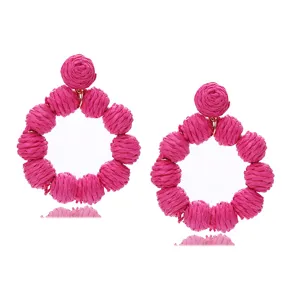 Close-up of pink raffia woven round earrings, showcasing fine texture and summer style details.