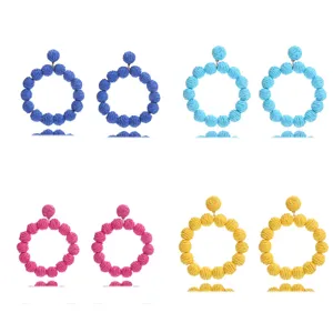Bohemian woven straw circular drop earrings detail view, multi-color summer beach vacation style jewelry.