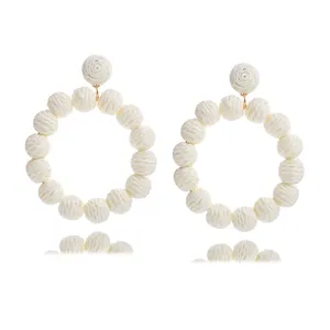 Handmade woven straw rattan round earrings detail, bohemian summer beach style jewelry.