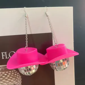 Detailed view of 70s disco style earrings featuring pink cowboy hats and shiny mirror balls.