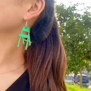 Gros plan détaillé montrant les boucles d'oreilles uniques en acrylique vert pailleté.