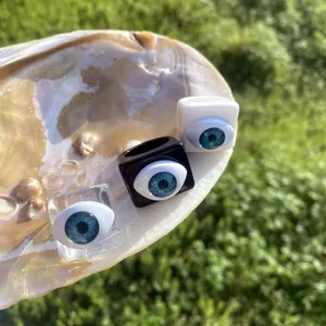 Nahansicht von Acrylharz-Quadratringen mit blauen bösen Blick-Motiven, stilvoller Modeschmuck.