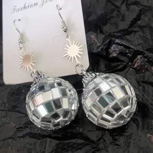 Primo piano dettagliato di orecchini pendenti argento con sfera disco e sole su cartellino.