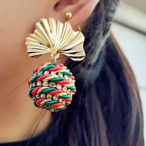 Gros plan de boucles d'oreilles pendantes feuille de ginkgo dorée rétro et boule strass.
