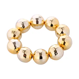 Dettaglio in primo piano di bracciale anello sfera palla disco in metallo dorato, gioiello da festa.
