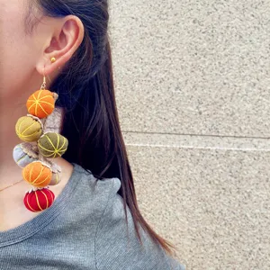 Primer plano detallado de pendientes de borla de calabaza de tela vintage de otoño.