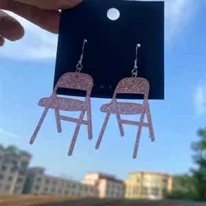 Gros plan detail de boucles d'oreilles chaises pliantes acrylique pailleté rose unique.