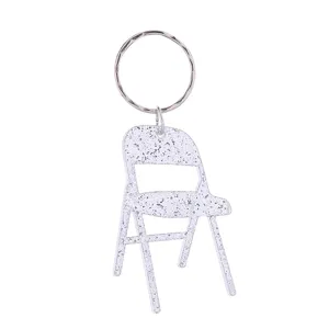 Nahaufnahme eines silbernen Glitzer-Mini-Klappstuhl-Schlüsselanhängers, Metallring.