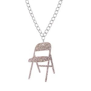 Gros plan détaillé d'un collier pendentif chaise pliante en acrylique pailleté argent.