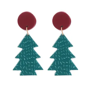 Nahaufnahme von Weihnachtsbaum-Ohrhängern mit roten Ohrringen und grünen Anhängern für Festtage.