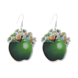 Primo piano di orecchini pendenti in legno mela verde, gioielli moda leggeri chic.