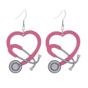 Close-up view of pink heart stethoscope wooden earrings, medical nurse theme jewelry detail.