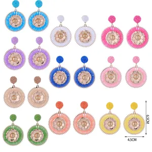 Boucles d'oreilles de fleurs en métal et raphia tissé fait main style boho vacances.