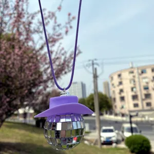 Detailansicht des hängenden Auto-Diskokugel-Ornaments mit lila Cowboyhut und Kordel.