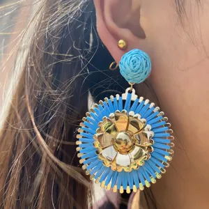 Boucles d'oreilles pendantes fleurs en raphia bleu et métal doré, parfaites pour les vacances.