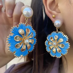Nahaufnahme von böhmischen blauen Raffia-Blumenohrringen mit goldenen Blütenblättern.