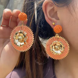 Boucles d'oreilles statement en raphia fait main et fleur d'or, vue detaillee style boheme.