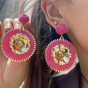 Superbes boucles d'oreilles pendantes en raphia tissé rose et métal, style vacances.
