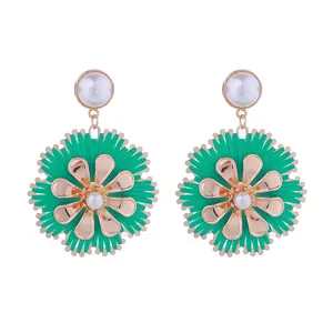 Nahaufnahme des grünen Bast geflochtenen Blumenohrsrings mit Metallblüten und Perle.