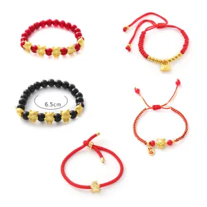Detailansicht von chinesischen Sternzeichen-Drachen-Charm-Armbändern mit roten Perlen und Gold.