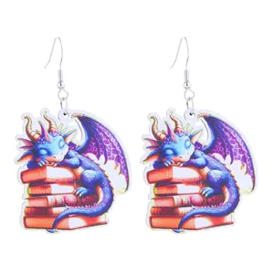 Close up details of cute fantasy dragon and books wooden earrings with metal hooks.