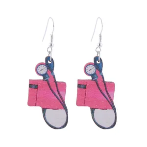 Dettaglio orecchini in legno stampato tema medico, orecchini pendenti con stetoscopio creativo.