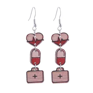 Close-up detail of nurse day medical wooden drop earrings featuring heart ekg and pill charms.