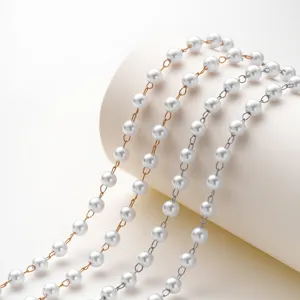 Dettaglio in primo piano di catene di perle multi-filo con maglie oro e argento per gioielli DIY.