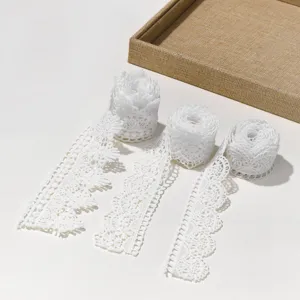 Detailed shot of white hollow water-soluble lace trim, delicate embroidery fabric accessory.