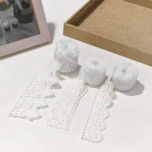 Detail view of white polyester embroidery lace trim, delicate hollow-out floral design for DIY crafts.
