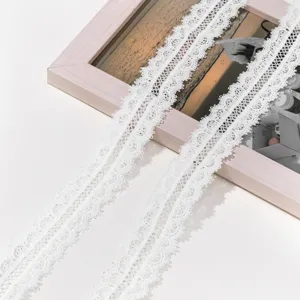 Closeup view of white hollow water-soluble lace trim, delicate embroidery fabric for DIY crafts.