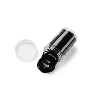 Close up of black elastic hair ties stored in a transparent plastic jar detail view.