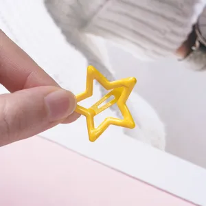 Close-up of yellow hollow star hair clip, cute metal BB clip detail for children hair styling.