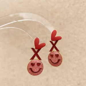 Detailaufnahme romantischer roter Herz und glitzernder Smiley Ohrringe für Damen.