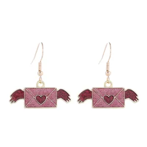 Detailaufnahme der romantischen rosa glitzernden Briefumschlag Ohrringe mit roten Flügeln.